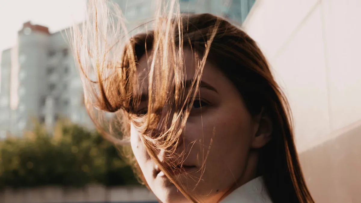 Woman outdoors with her hair blowing across her face in the wind