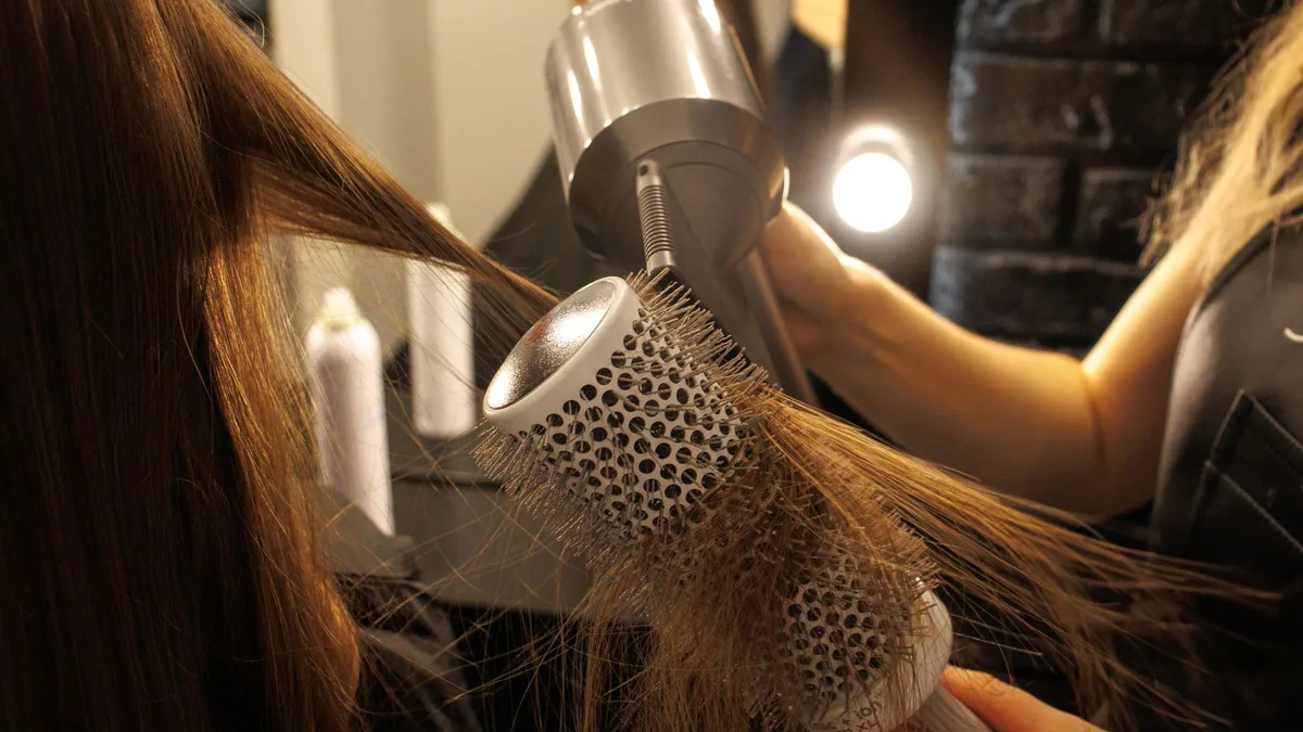 Stylist blow-drying long hair with a round brush