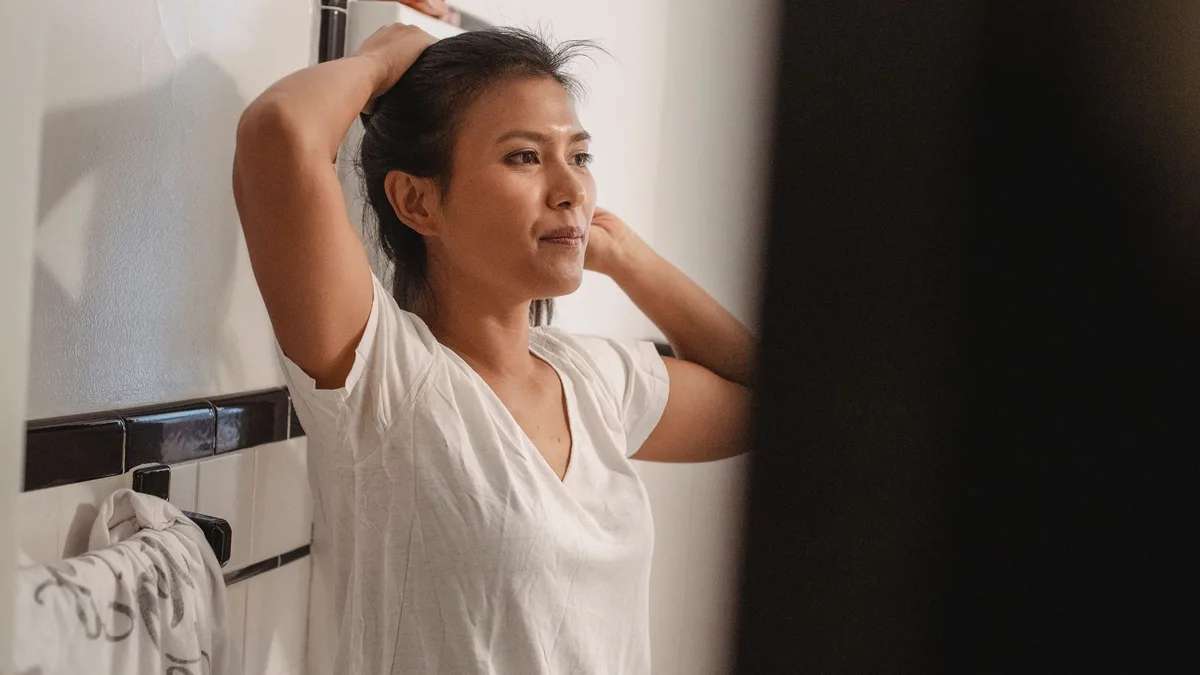 Woman drying and styling her hair at home in the bathroom