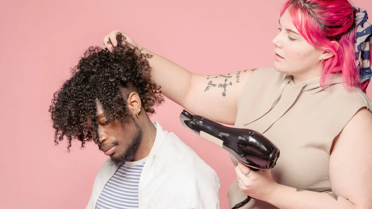 Hairdresser drying a client's curly hair with a hairdryer