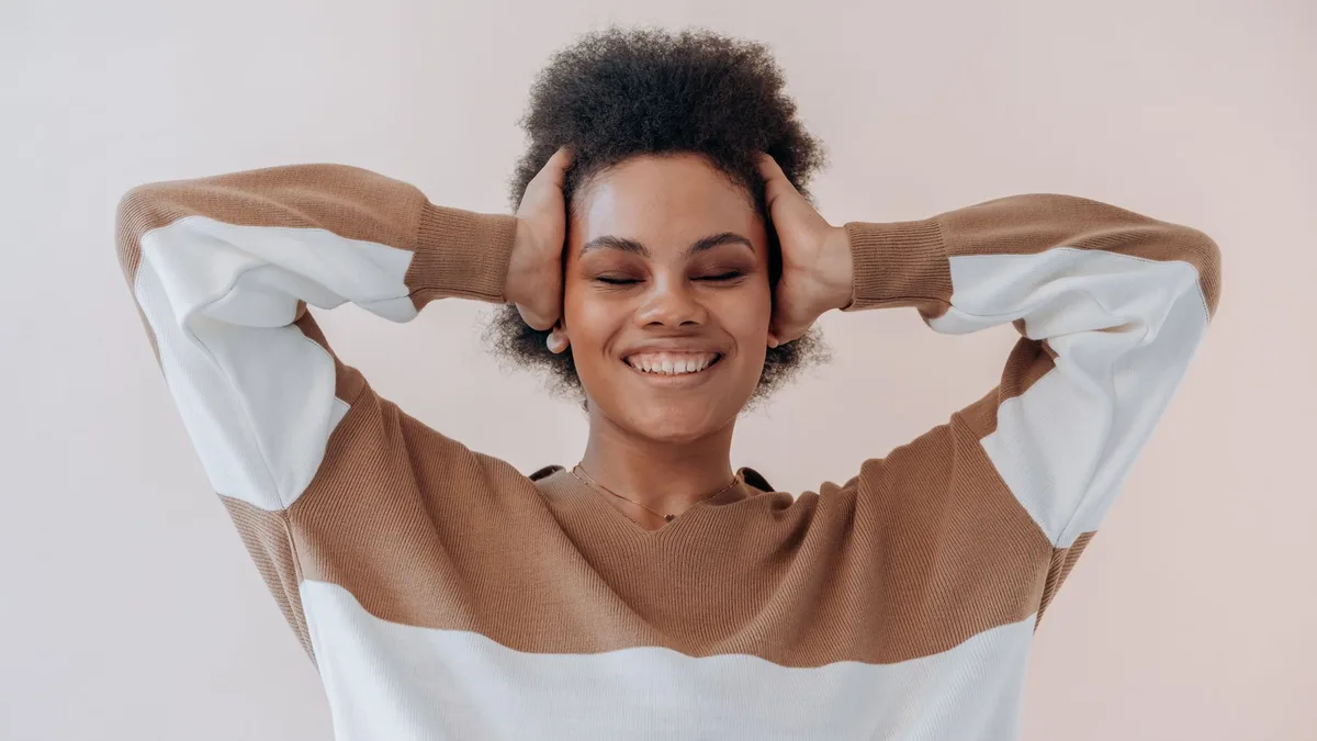 Smiling woman scrunching her afro hair with both hands