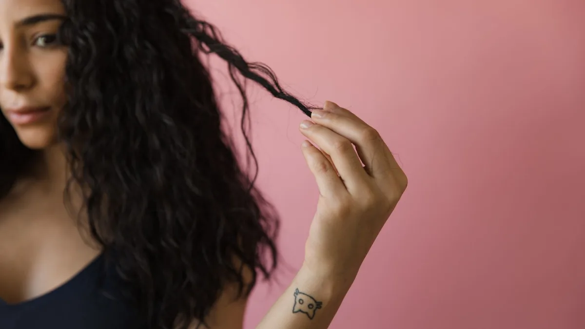 Woman examining a section of her curly hair