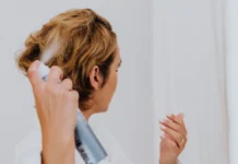 Curl Refreshing Spray: How to Revive Day-3 Curls Without Washing Woman spraying her hair with a curl refreshing spray