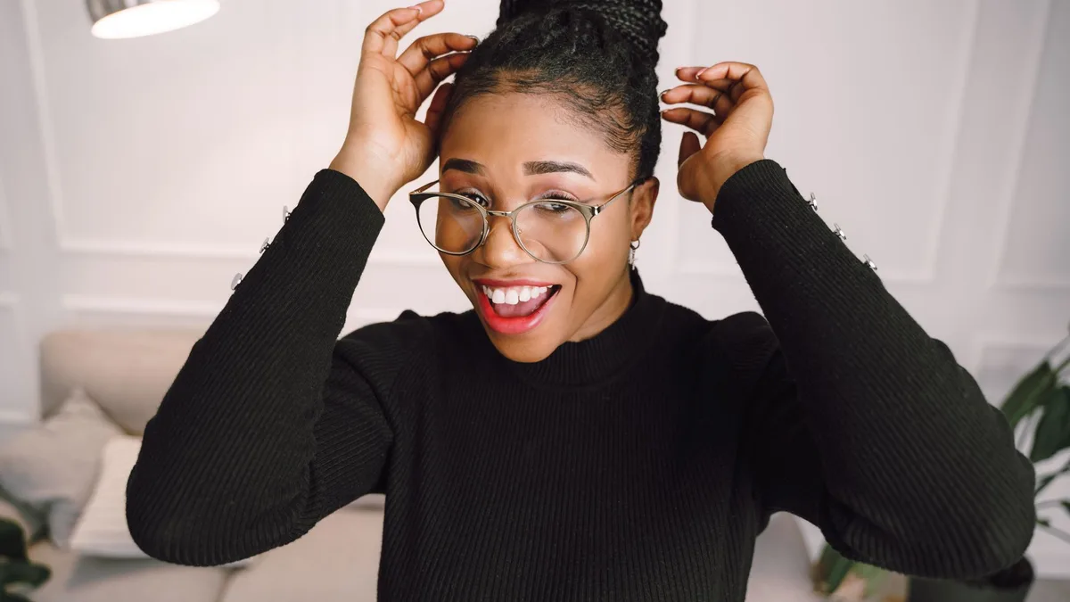Smiling woman gathering her curly hair into a loose high bun