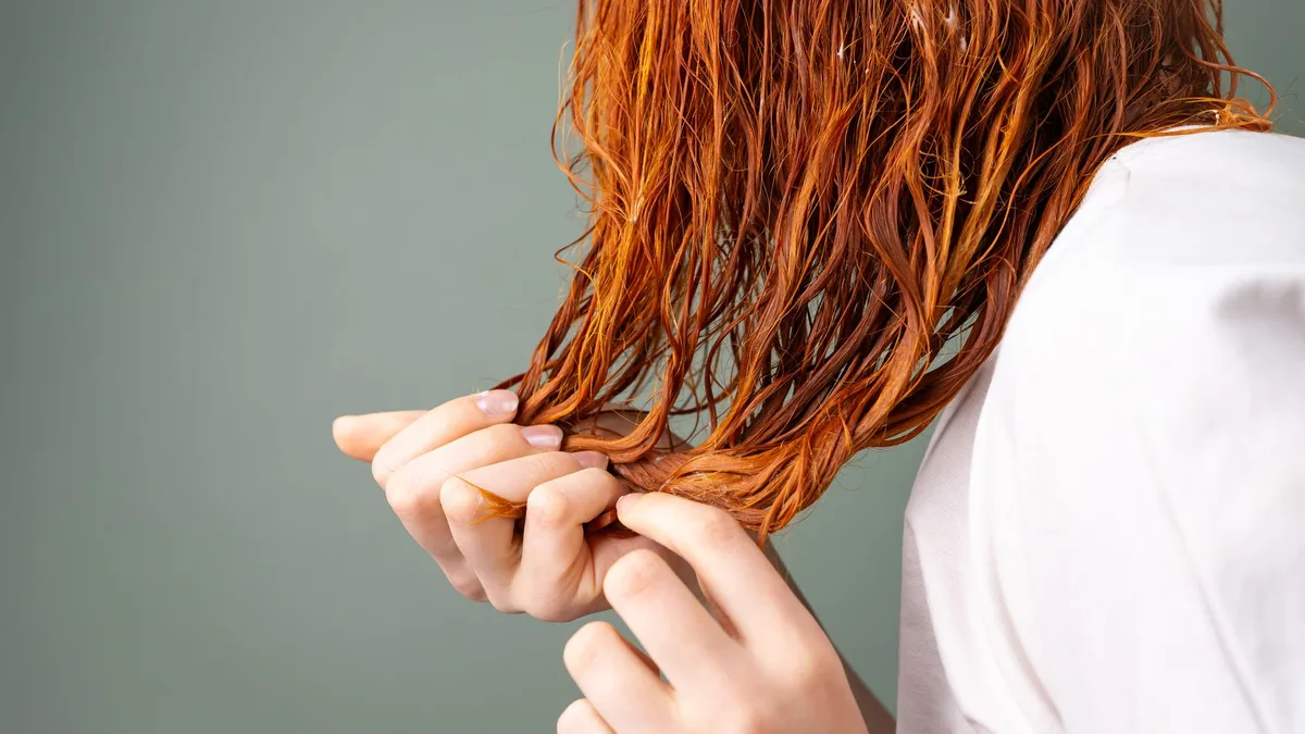 Close-up of hands holding a section of wet hair to check its condition