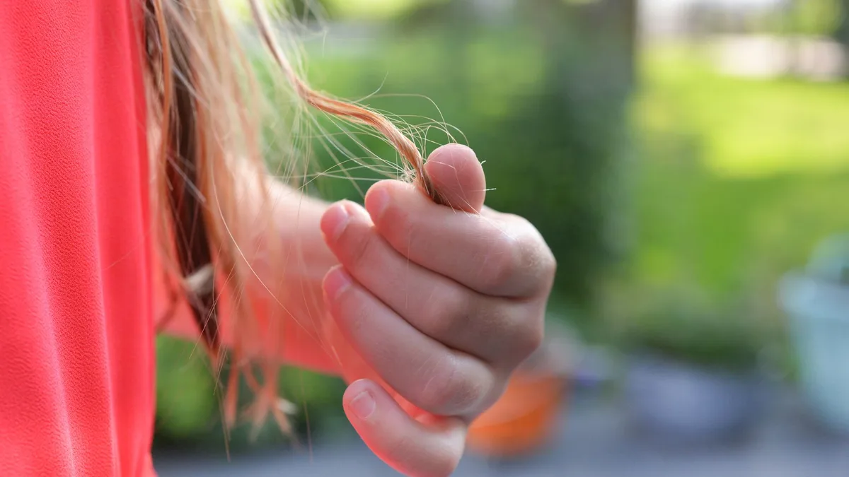 Person holding a strand of long hair to inspect the ends