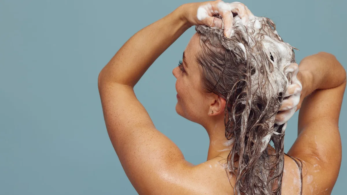 Woman washing her long hair with lathered shampoo