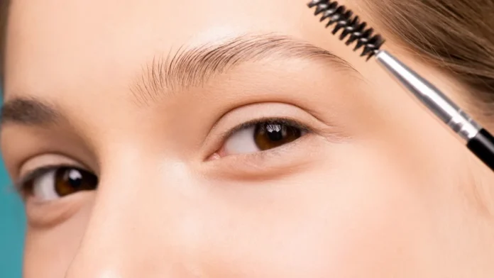 Woman grooming her eyebrows with a brow brush