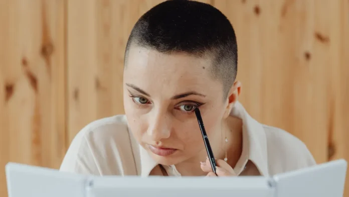Eyeliner Types Woman applying eyeliner while looking in a mirror