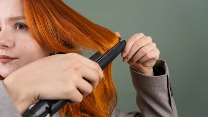 Woman styling her hair with a flat iron straightener