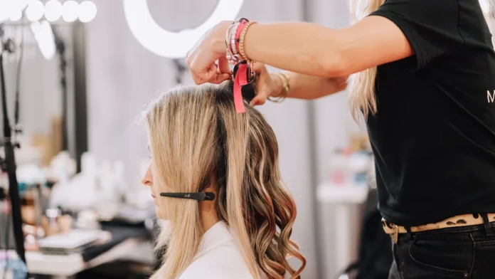 Hair Extensions and Wigs Stylist adding hair extensions to a woman's long hair