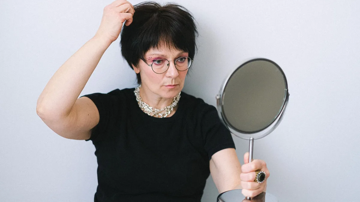 Woman checking her hair while holding a mirror