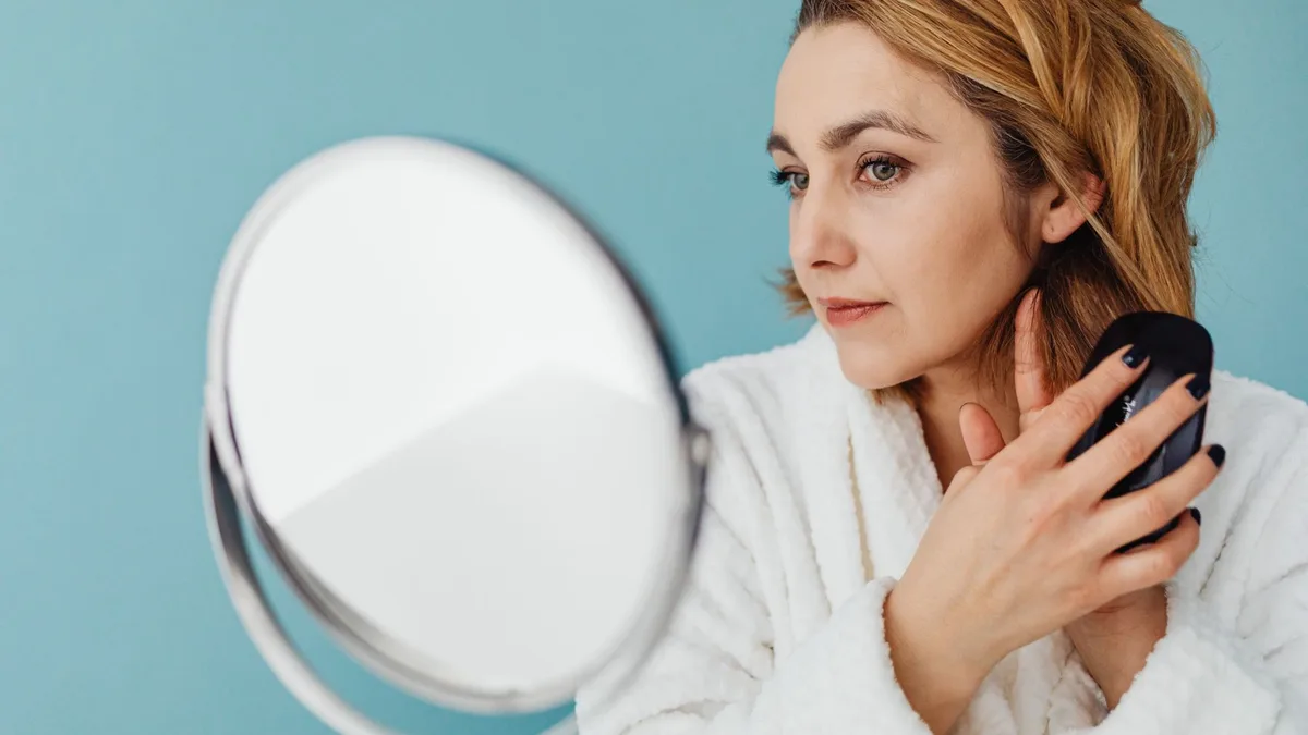Woman brushing her hair in front of a mirror