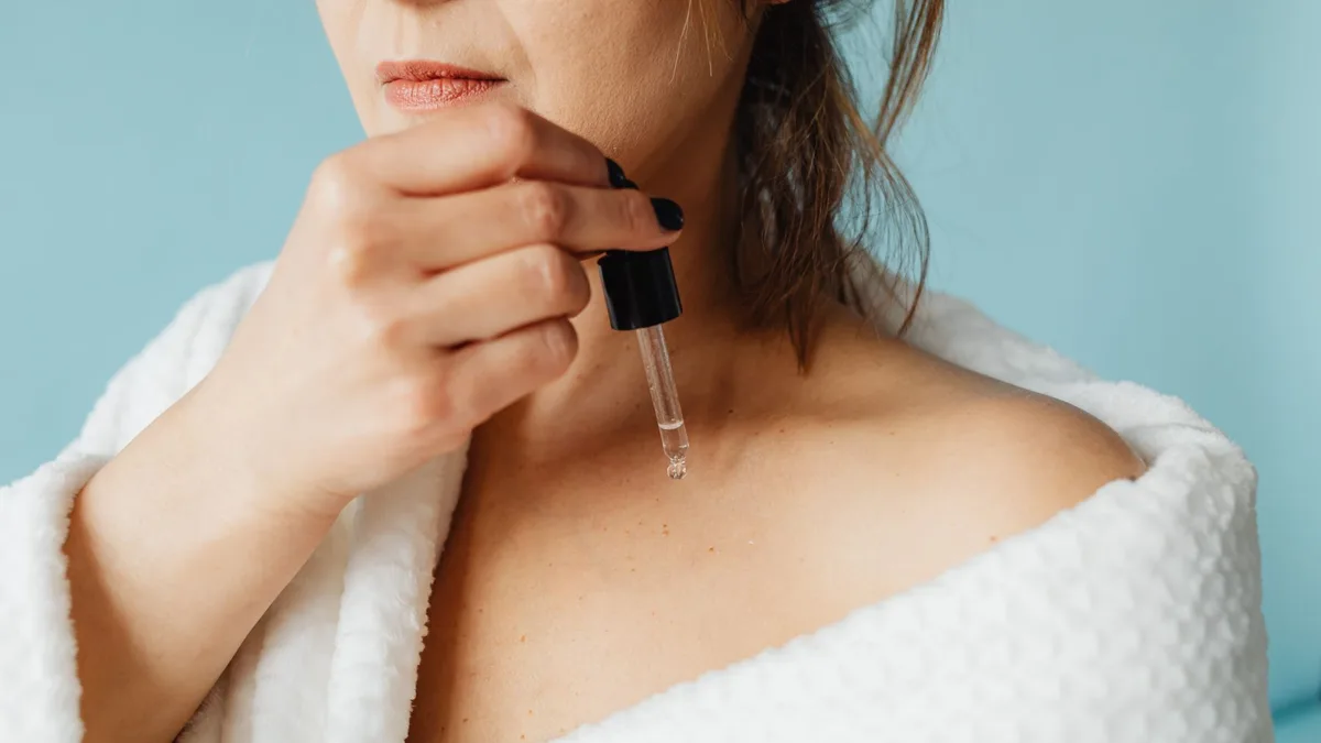 Woman in a bathrobe applying a treatment serum