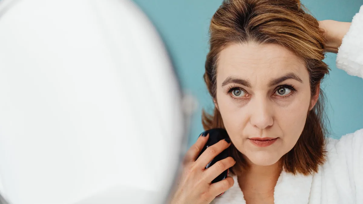 Woman styling her hair while looking in a mirror