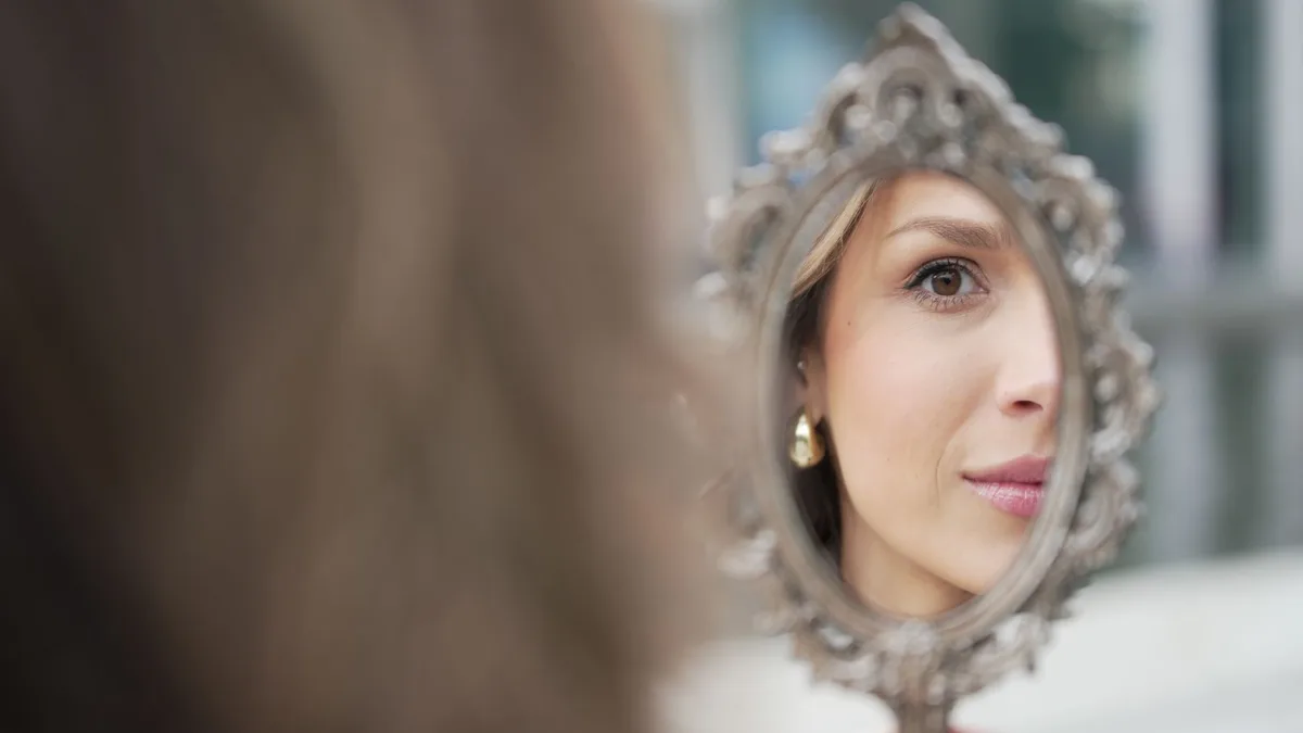 Woman examining her reflection in a handheld mirror