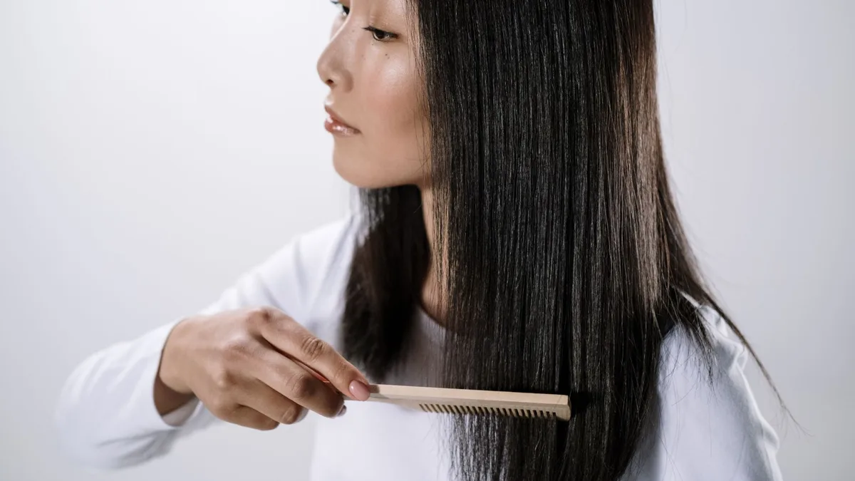 Woman with long smooth straight hair combing it in a studio