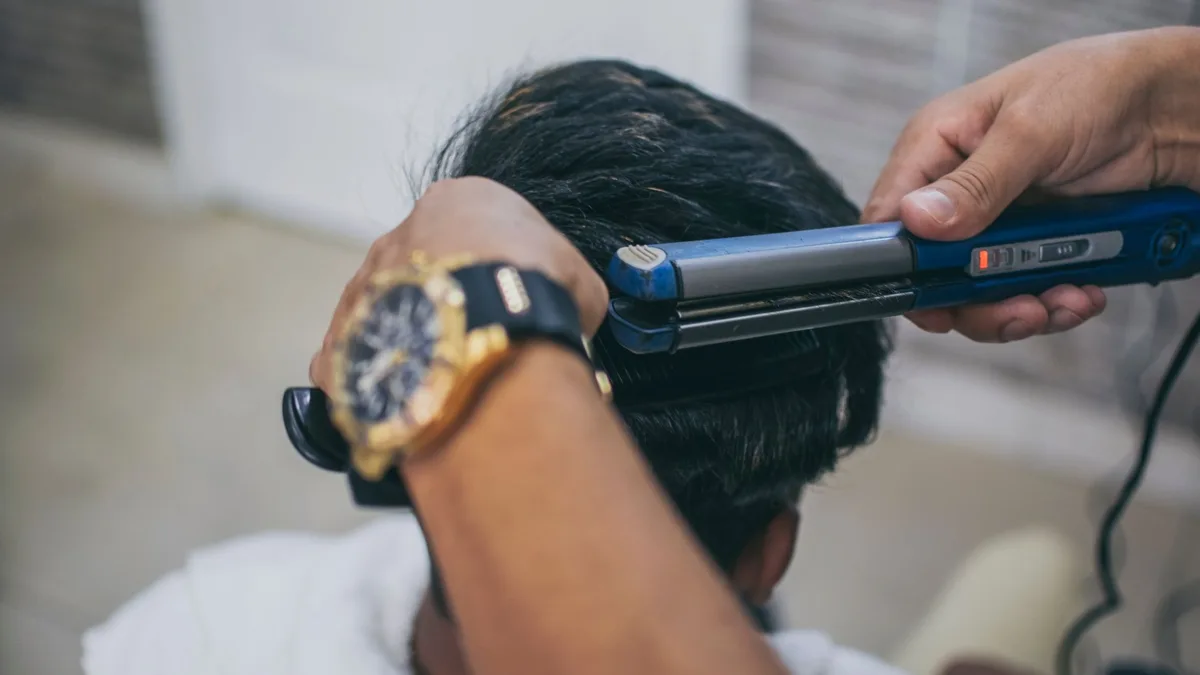 Stylist sealing a section of hair with a straightener