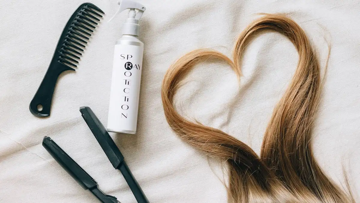 Flat lay of hair styling tools including straightener and brushes