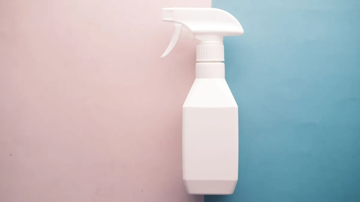 A white spray bottle on a plain pastel background