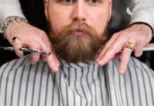 Men’s Grooming Guide: Beard, Shave and Skin Basics Bearded man receiving grooming at a barbershop