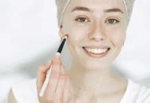 How to Reapply Sunscreen Over Makeup Without Ruining It Woman touching up sun protection over her makeup with a brush