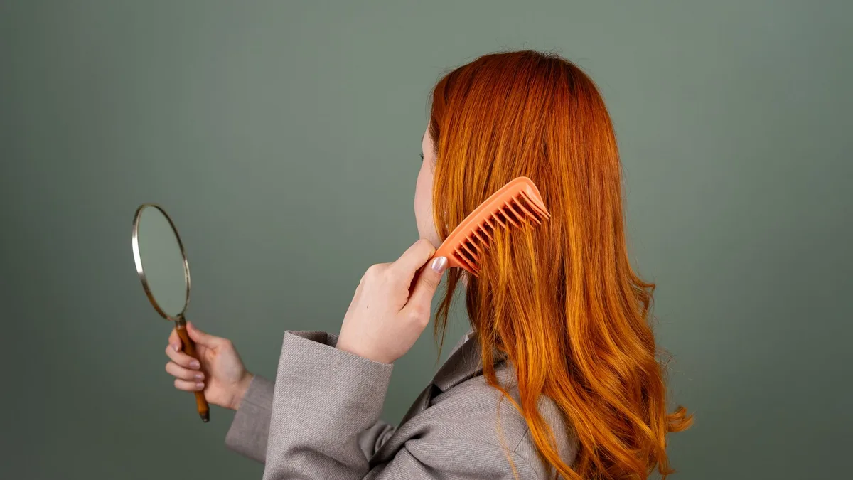 Woman checking her hair parting in a hand mirror