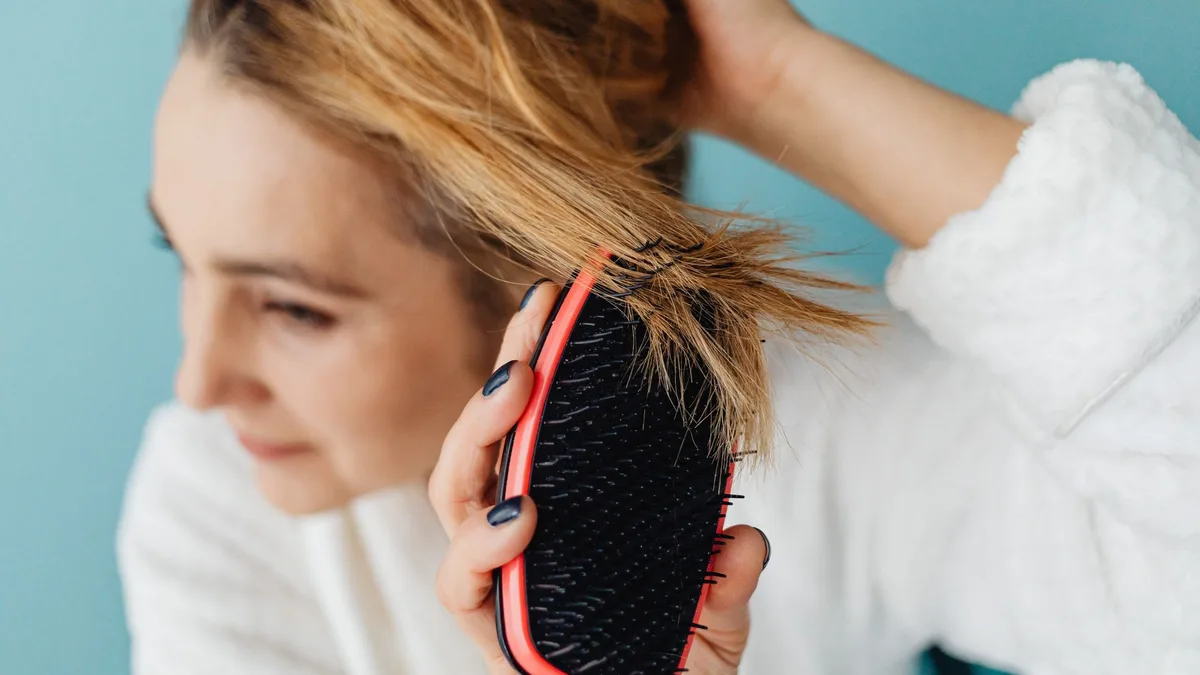 Close-up of a woman brushing her hair at the parting