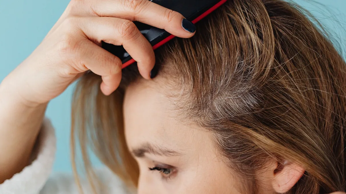 Woman brushing her hair and checking the roots