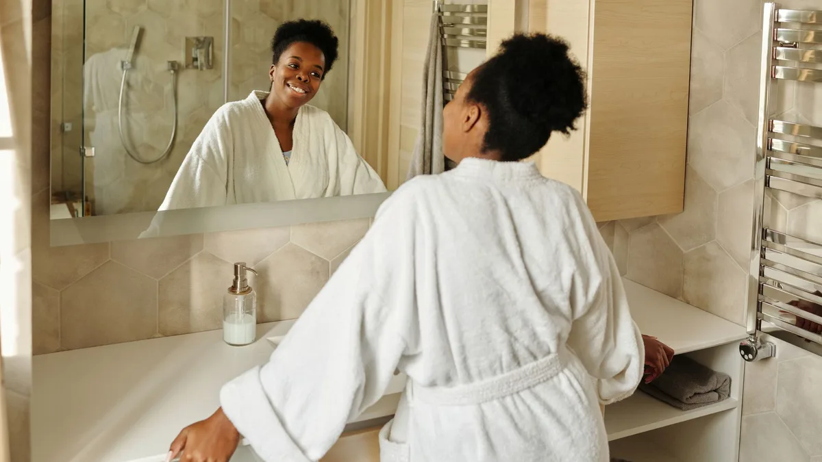 Woman smiling at her reflection in a bathroom mirror
