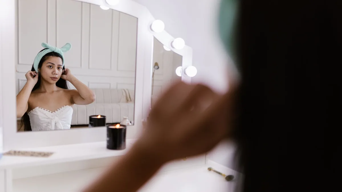 Young woman at a vanity mirror adjusting her hair