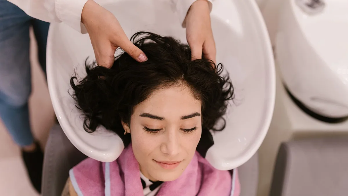 Woman having her scalp massaged and washed at a salon basin