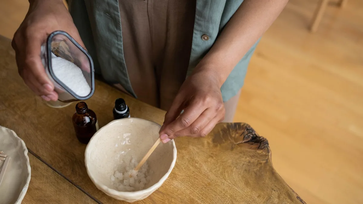 Hands mixing a natural sugar and salt scrub in a bowl