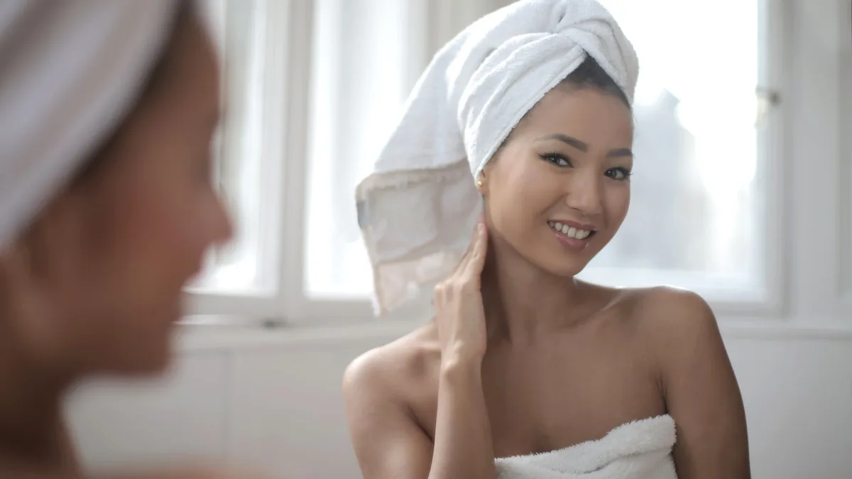 Woman wrapped in a towel smiling in a bright bathroom