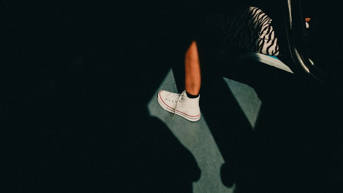 Person wearing white trainers in strong sunlight