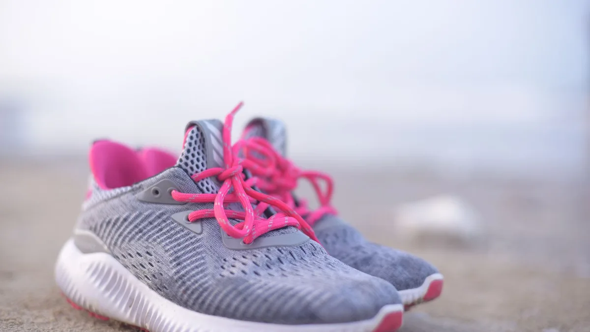 Pair of modern trainers resting on sand