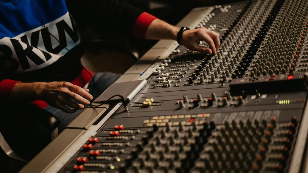 Engineer adjusting levels on a studio mixing console