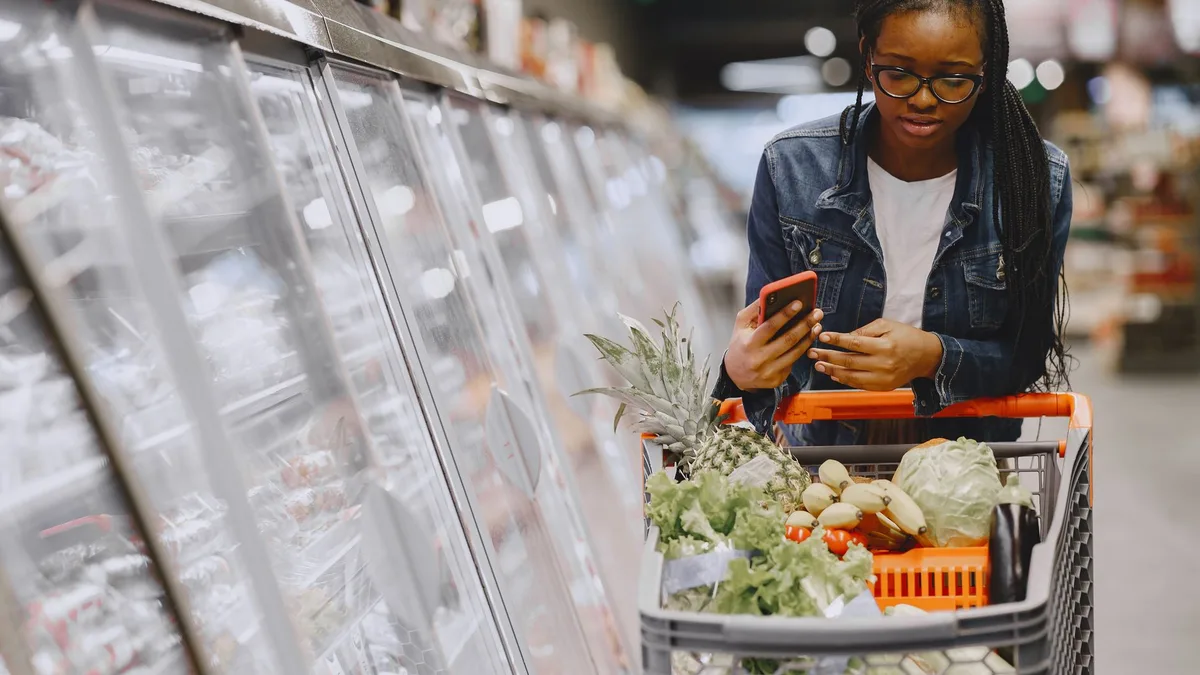 Woman checking her phone while shopping in a grocery store