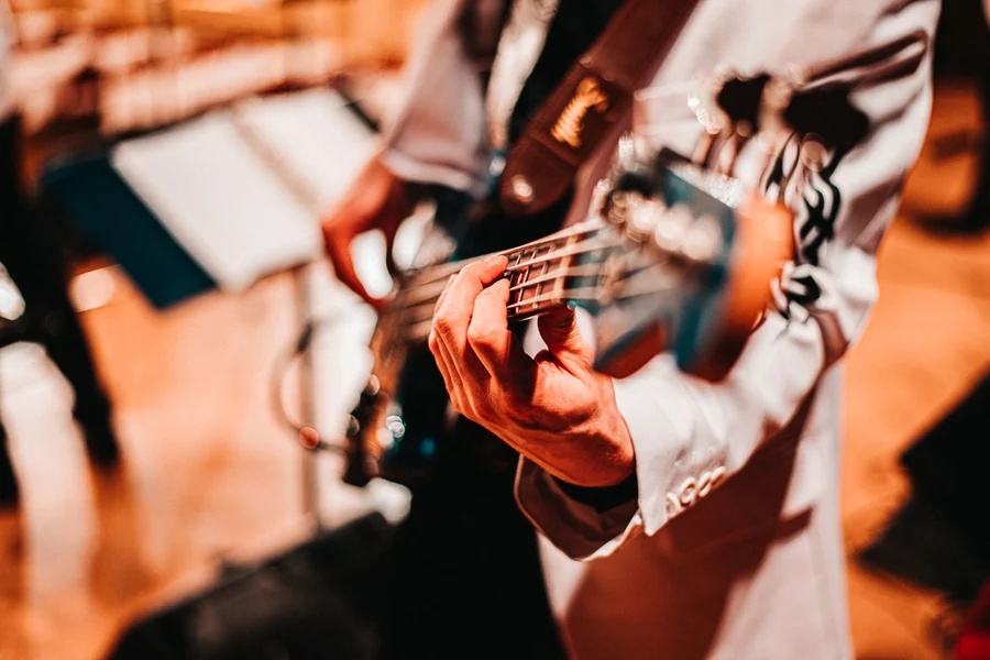 Bill Wyman net worth - musician playing a bass guitar against a blurred background