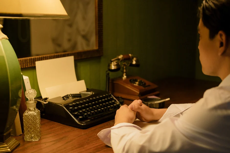 Dick Cavett net worth - man at a desk with a typewriter and lamp