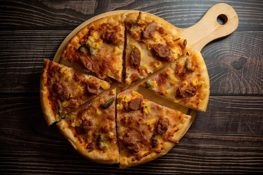 Double cut pizza - sliced homemade pizza on a rustic wooden board