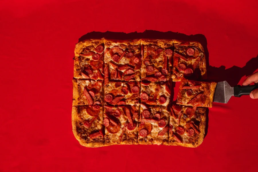 Double cut pizza - rectangular pizza pieces served on a red surface