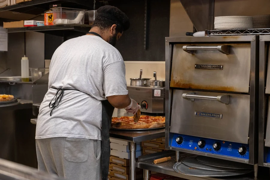 Double cut pizza - chef slicing a freshly baked pizza in a kitchen