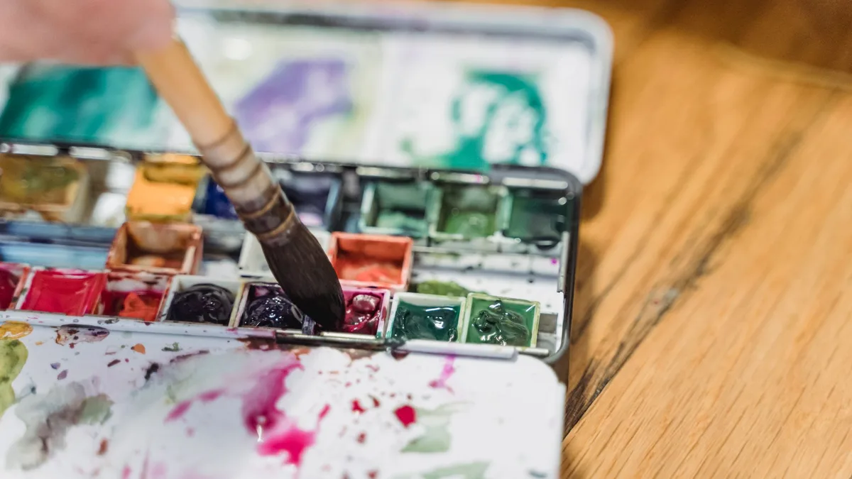 Watercolour palette and paintbrush on a work surface