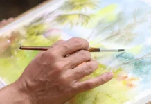 Frances Henriques Net Worth 2026: What Is Actually Known About Sean Paul’s Mother Artist painting a watercolour landscape with a fine brush