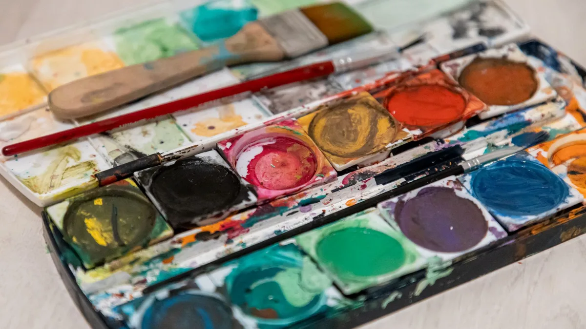 Watercolour paints and brushes arranged on a table