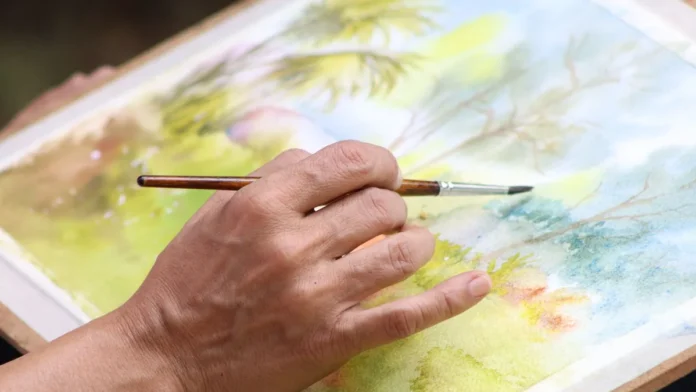 Artist painting a watercolour landscape with a fine brush