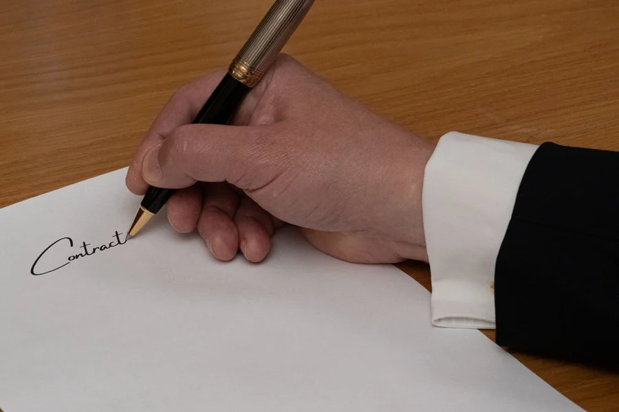 Louis Walsh net worth - professional signing a contract with a fountain pen