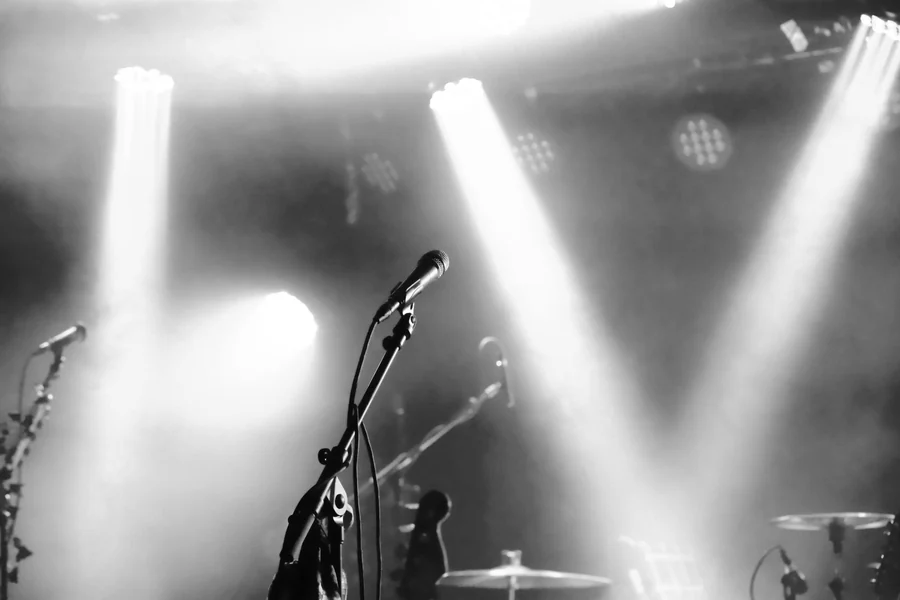 Louis Walsh net worth - black and white stage with microphones and spotlights