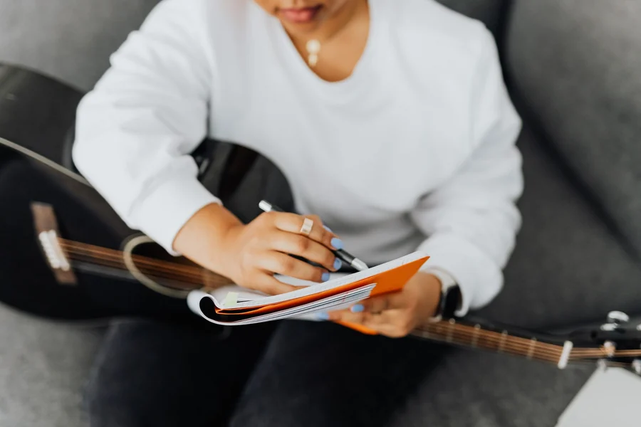 Taylor Swift net worth - songwriter writing music notes in a notebook with a guitar